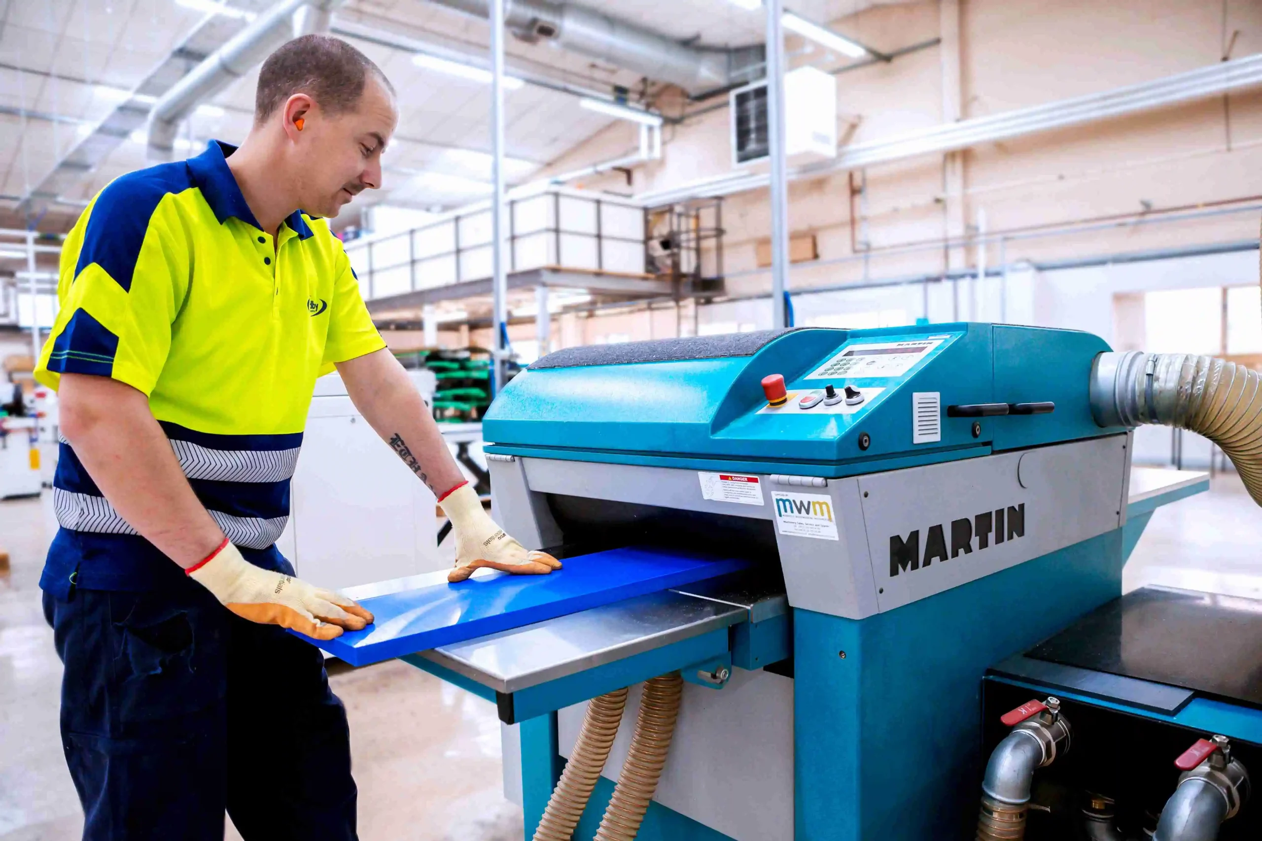 Planing services at Oadby Plastics with a machine operator and a sheet of semi-finished plastic material