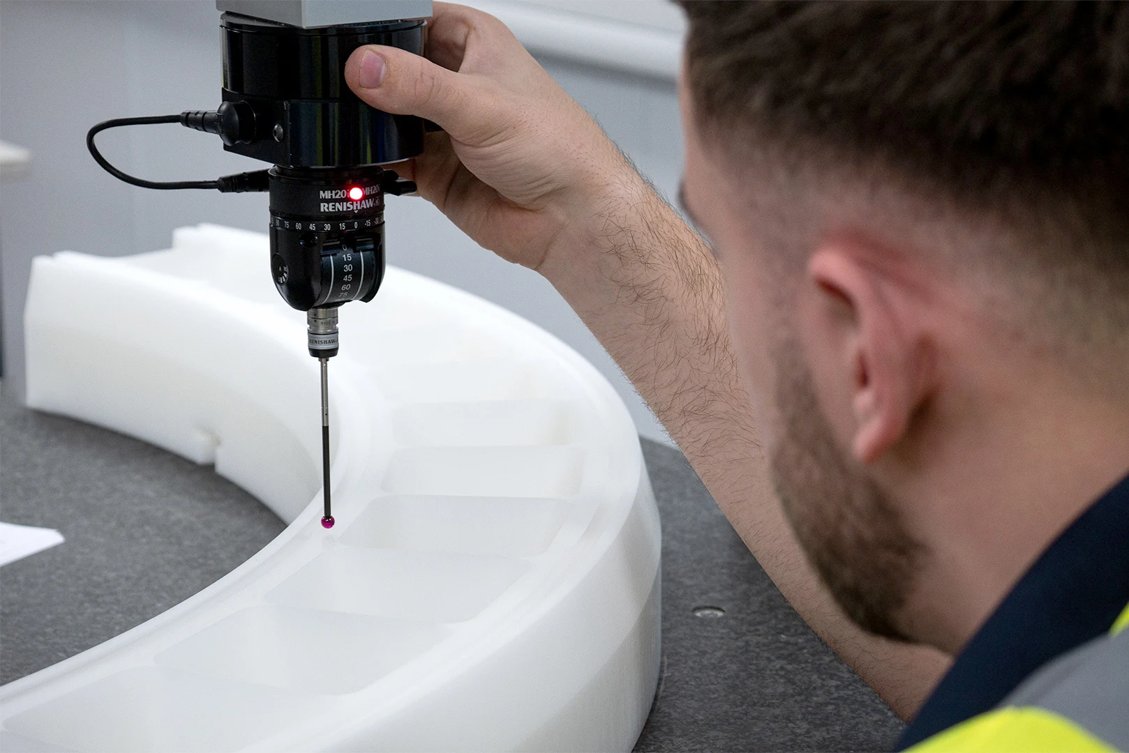 Close-up of a man doing QA for a piece of machined plastic at Oadby Plastics