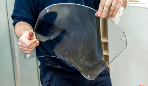 An Oadby Plastics production worker holding a fabricated piece of clear plastic that has used the drape forming technique