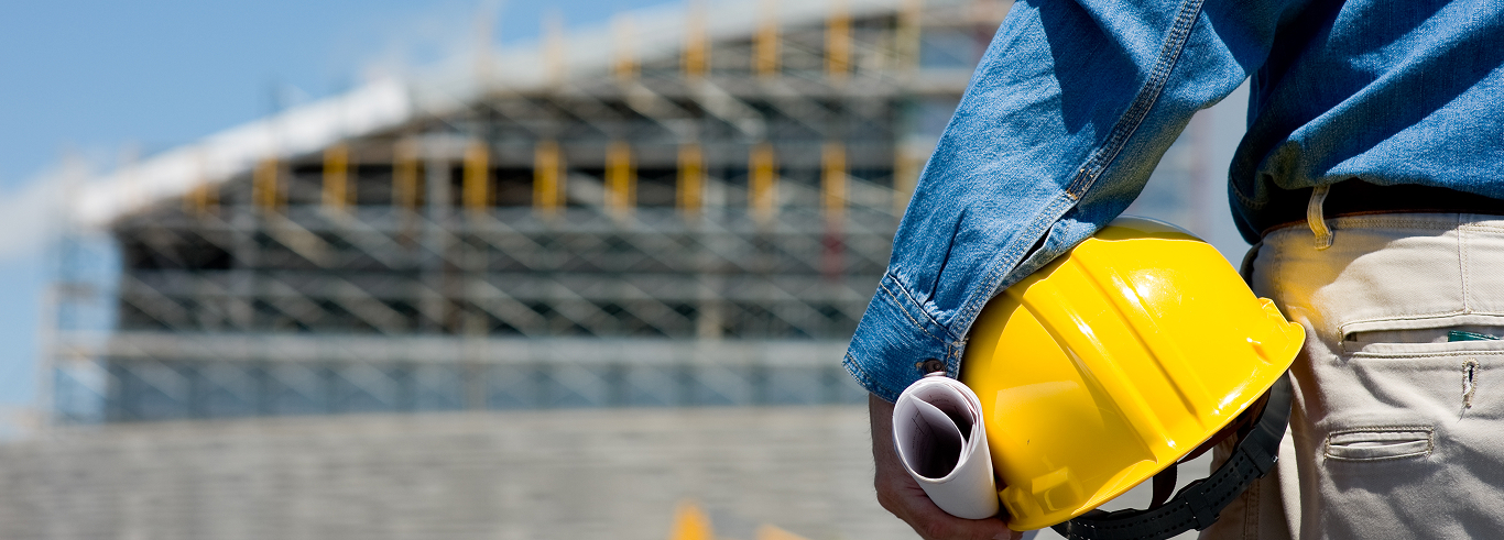 A workman with his hard hat and building plans under his arm, including specified engineering plastics