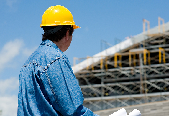 Builder looking at plans with a hard hat and using engineering plastics specified by Oadby Plastics