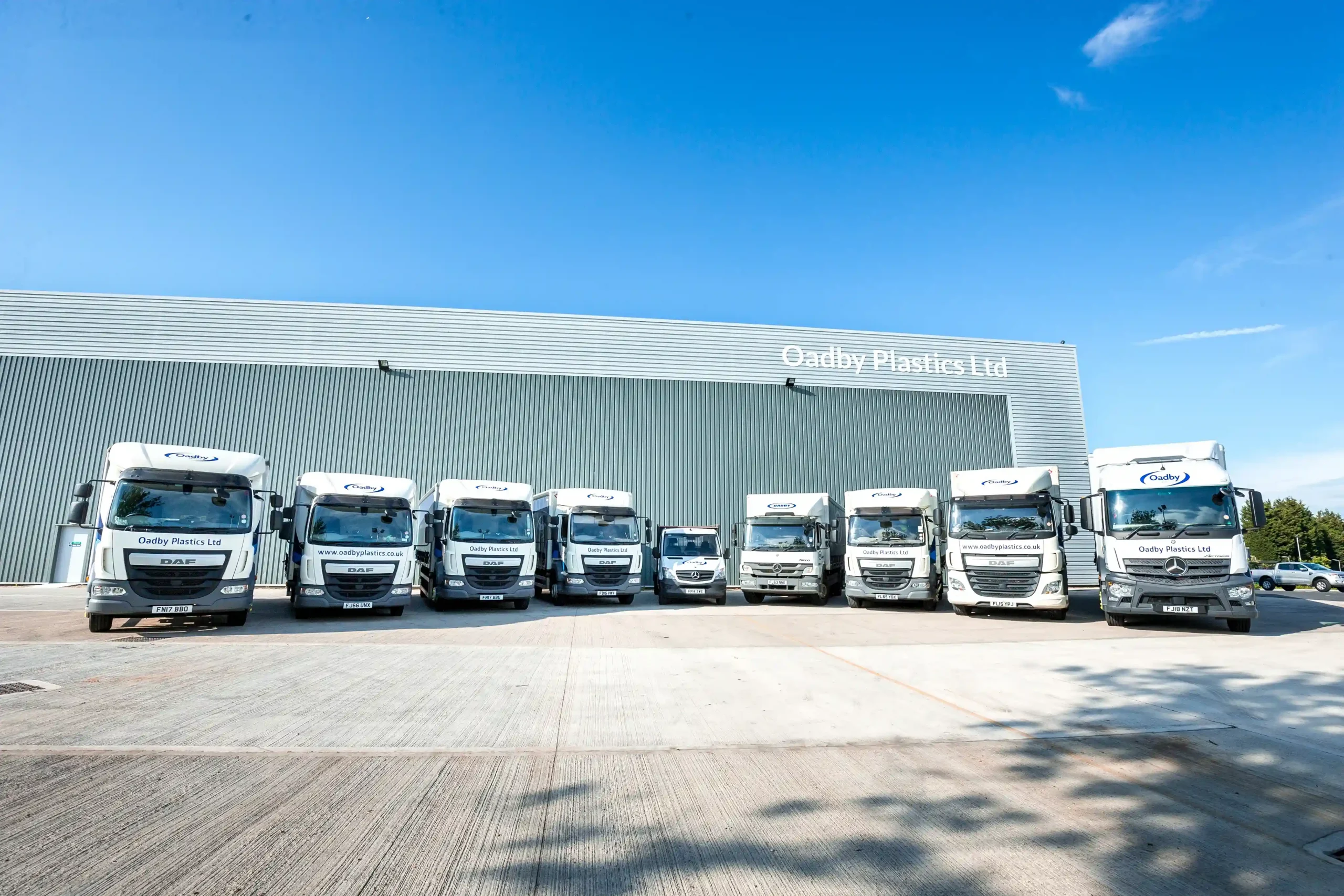 A fleet of different sized vehicles at Oadby Plastics head office in Leicester ready to delivery across the UK on a sunny day with blue skies