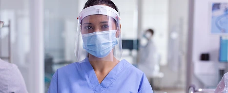 A female doctor wearing a clear plastic face shield with high chemical resistance for protection