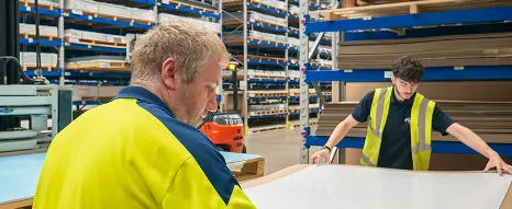 An experienced worker and an apprentice at Oadby Plastics handling a sheet of plastic on a cardboard base as they prepare to carefully package the item