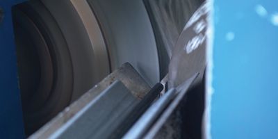 Close-up of a rod of plastic being fed into a grinding machine